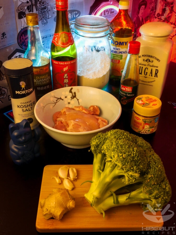 Raw, unprocessed ingredients for Chinese Broccoli and Chicken stir-fry are distributed on a table.