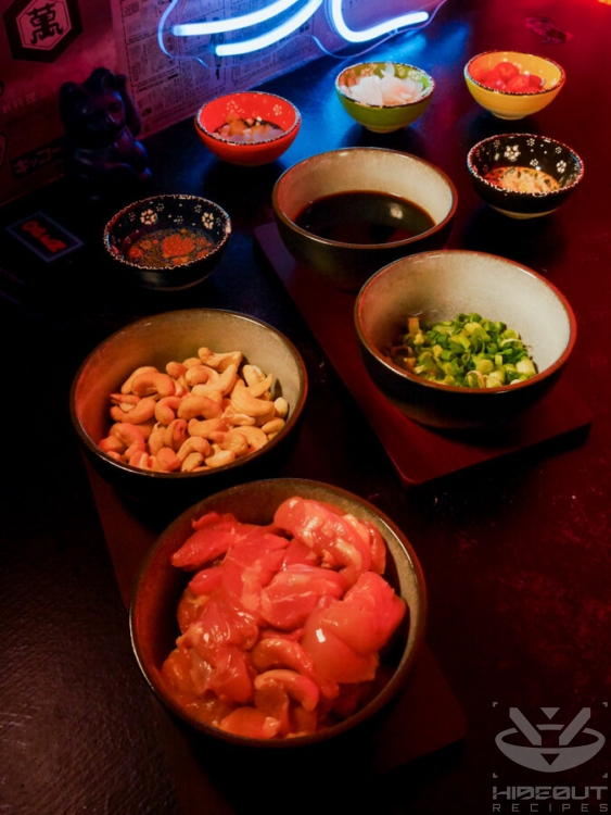 Small bowls containing ingredients for Thai Cashew Chicken are distributed across a table.