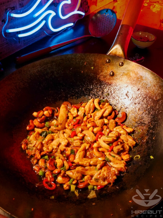 A futuristic Cyberpunk-style food photo. A wok filled with finished Thai Cashew Chicken is standing on a table.