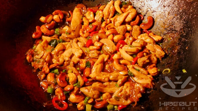 A futuristic Cyberpunk-style food photo showing a close-up of Thai Cashew Chicken in a large wok.
