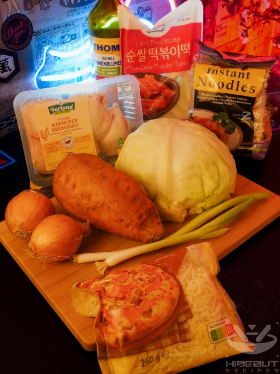 Ingredients for Korean Dakgalbi in their respective packaging are laid out on a table, with fresh vegetables in the foreground.