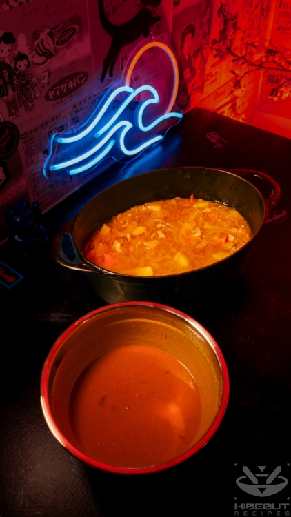 A large cast-iron pot containing half-made Japanese curry as well as a bowl containing dissolved curry cubes are ready to be mixed.