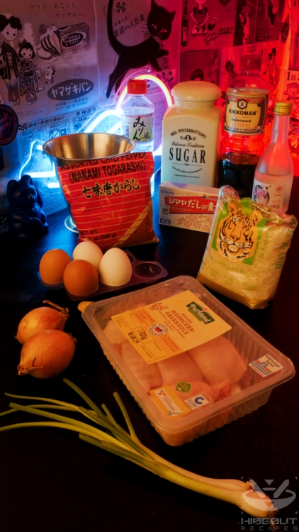 Ingredients for Japanese Oyakodon are laid out on a table in their packaging. Onions and green onions lie in the foreground.
