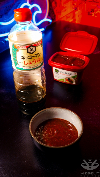 A bowl of Tteokbokki sauce with a bottle of soy sauce and a container of gochujang in the background.
