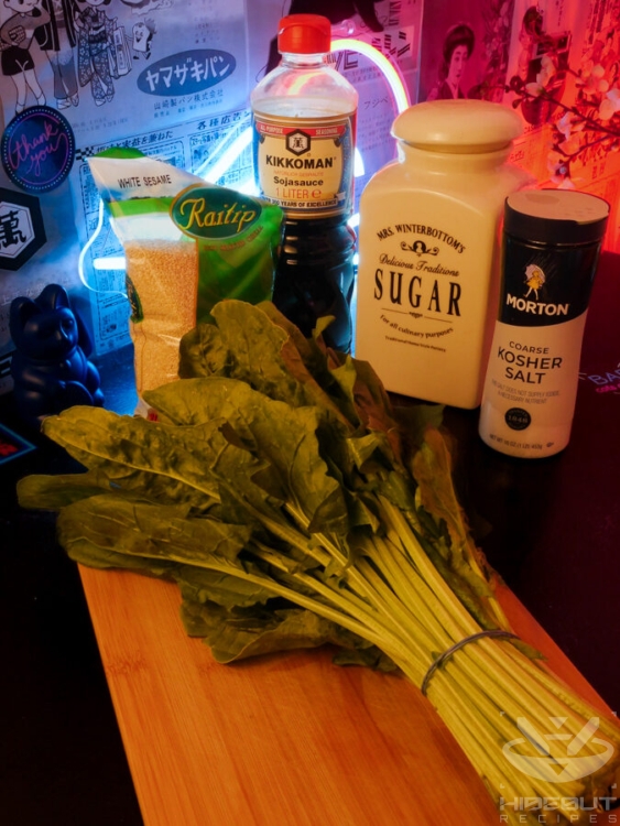Ingredients for Japanese sesame spinach are gathered on a table: A bunch of fresh spinach, salt, sugar, soy sauce, and white sesame.