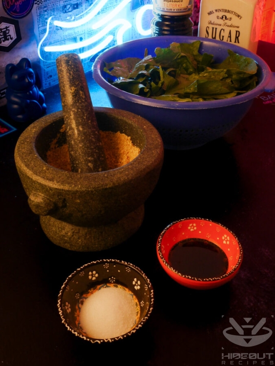 Pre-measured ingredients for Japanese sesame spinach are gathered on a table. The sesame is placed in a large mortar.