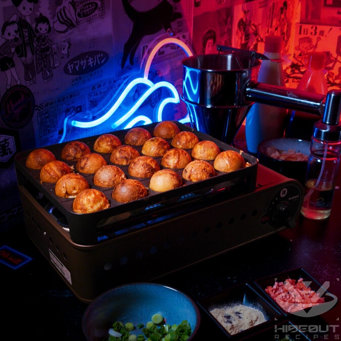 A specialized grill filled with Takoyaki ready for consumption, surrounded by more ingredients.