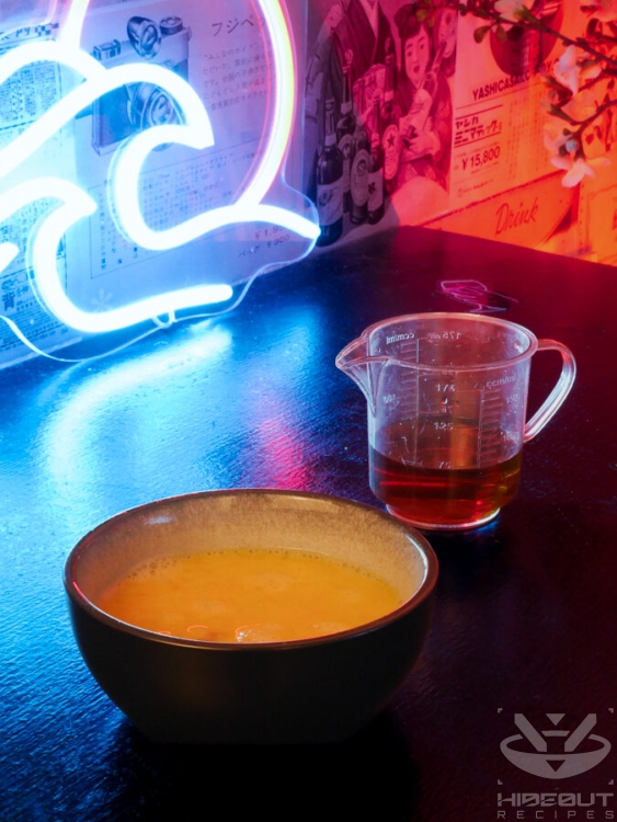 Beaten eggs in a bowl and pre-mixed seasoning for Tamagoyaki in a measuring cup are placed on a table.