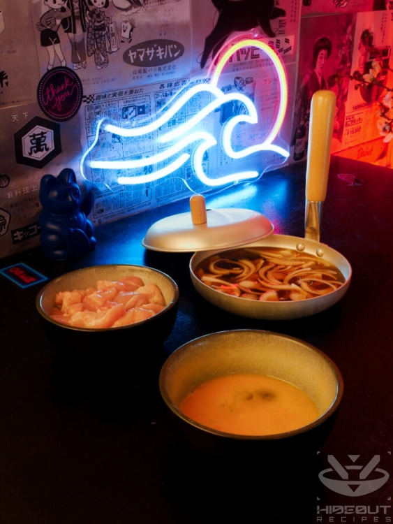 An Oyakodon pan filled with broth and a layer onions of sliced onions, a bowl of chopped chicken, and a bowl of beaten egg.