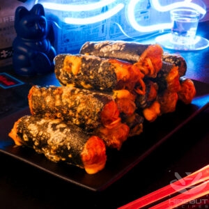 A futuristic Cyberpunk-style food photo. Spring rolls containing noodles in a spicy sauce, nori, and cheese are stacked up on a plate.