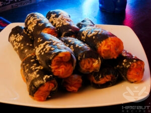 A stack of already folded spicy spring noodle rolls is lying on a table.