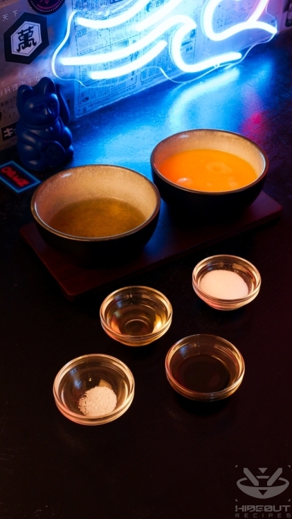 Tamagoyaki ingredients are distributed across a table in small bowls: beaten eggs, dashi, and additional condiments.