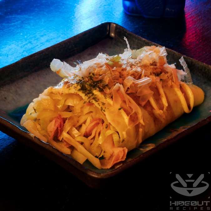 A futuristic Cyberpunk-style food photo. Half a Tonpeiyaki (Japanese pork and cabbage omelet) is lying on a plate, with the cut facing the viewer so the cabbage and bacon inside are visible.