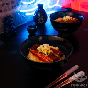 A futuristic Cyberpunk-style food photo showing a bowl of Unadon in front with glowing chopsticks beside it, and another bowl in the back.