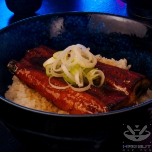 A futuristic Cyberpunk-style food photo showing a close-up of a bowl of Unadon (Japanese eel rice bowl).