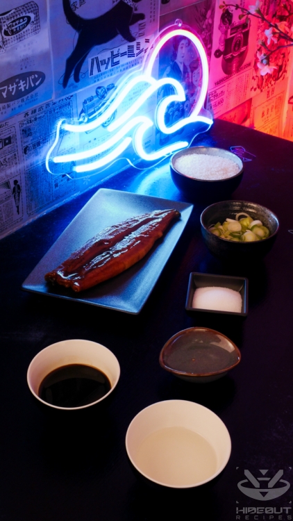 Prepared ingredients for Japanese Unadon (unagi donburi) are laid out on a table on plates and bowls.