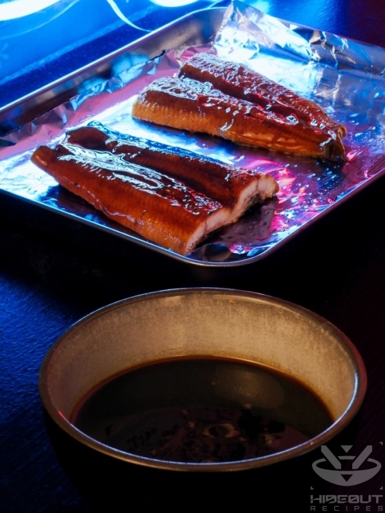 A bowl of sauce for unagi kabayaki in the front and two halves of an eel fillet in the back on oiled aluminum foil.