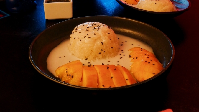 A futuristic Cyberpunk-style food photo showing multiple plates of Thai Mango Sticky Rice.